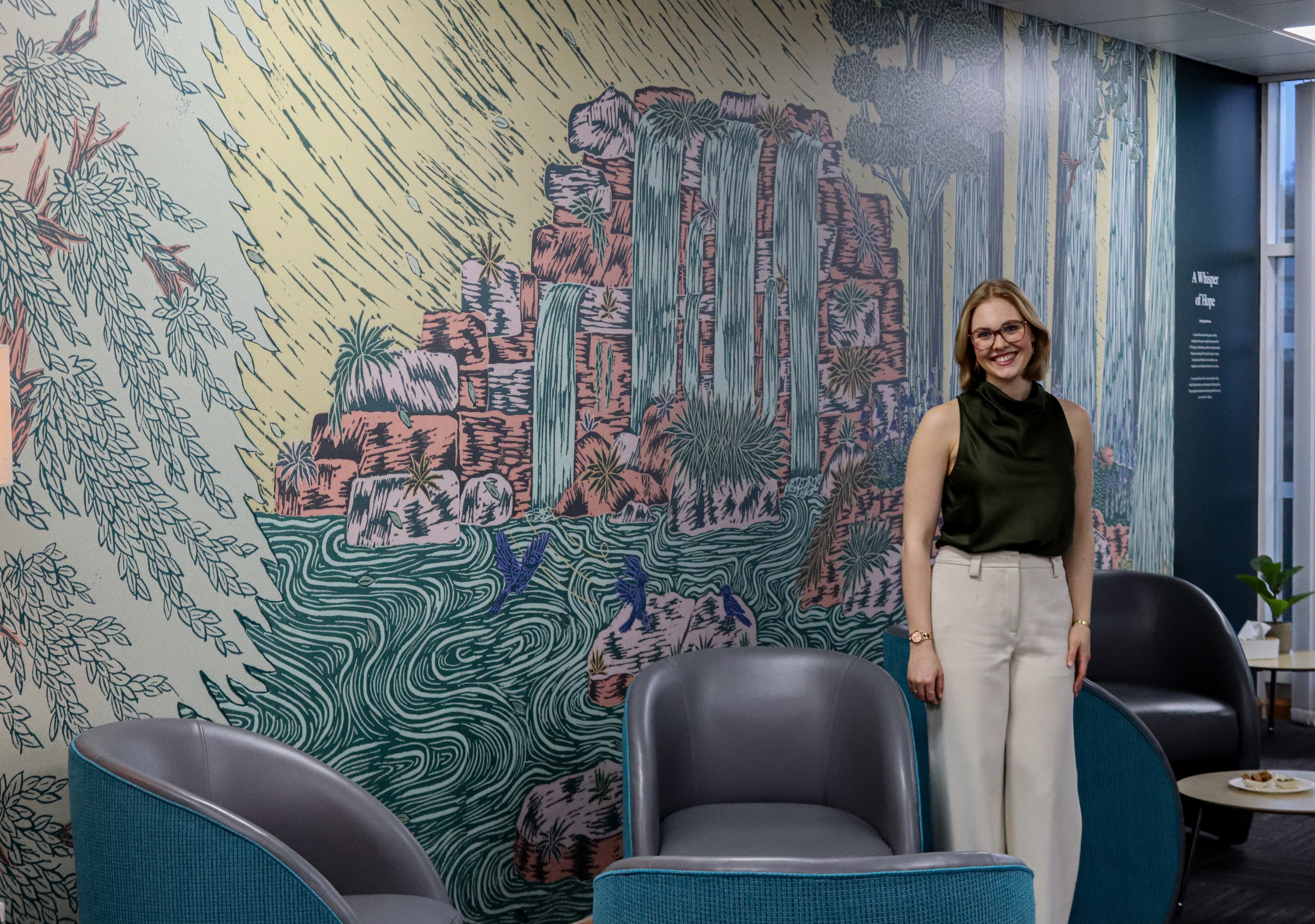 Poppy Robertson standing beside her mural at our Nottingham fertility clinic during the NTU Graphic Design partnership event.